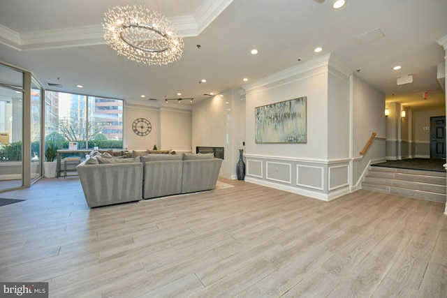 living room with crown molding, a chandelier, a fireplace, and light hardwood / wood-style flooring