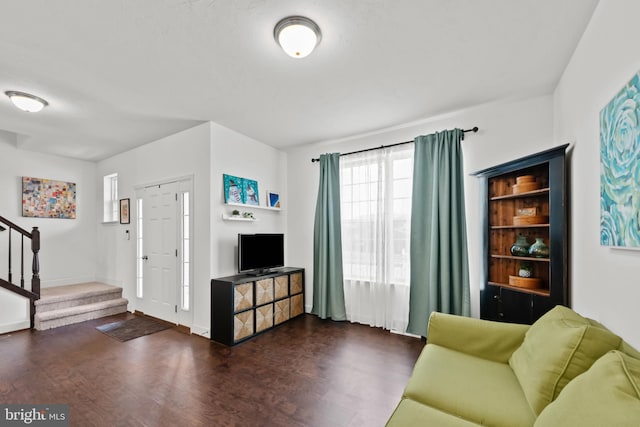 living area with baseboards, wood finished floors, and stairs