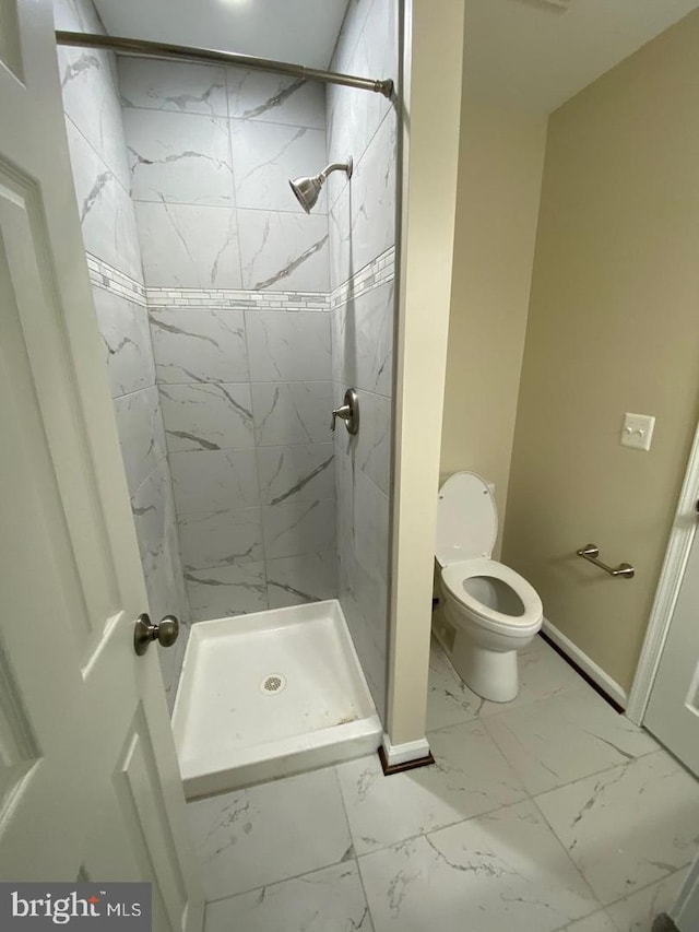 bathroom featuring a stall shower, marble finish floor, baseboards, and toilet