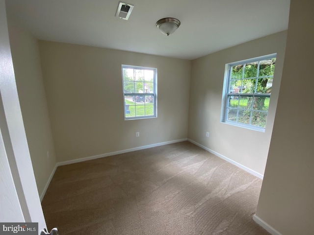 unfurnished room featuring carpet, visible vents, and baseboards