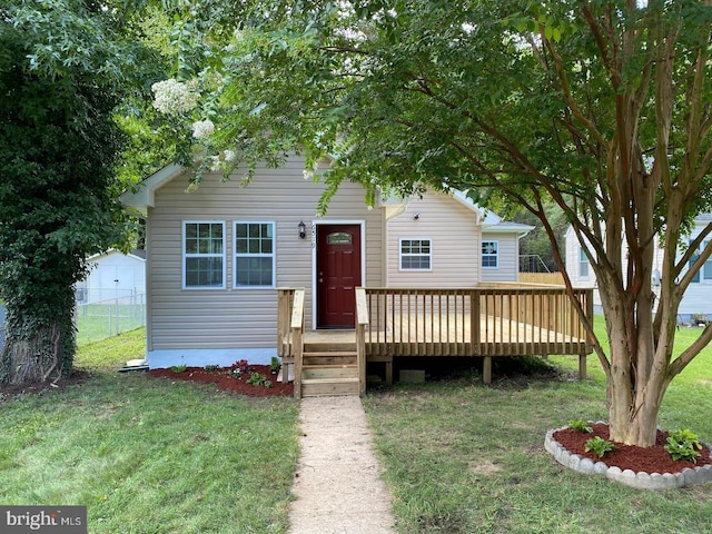 view of front of home with fence, a wooden deck, and a front lawn