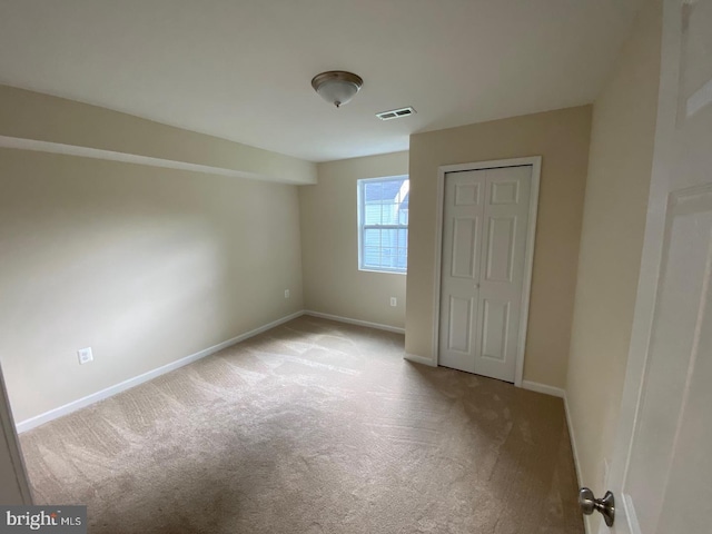 unfurnished bedroom with a closet, light colored carpet, visible vents, and baseboards