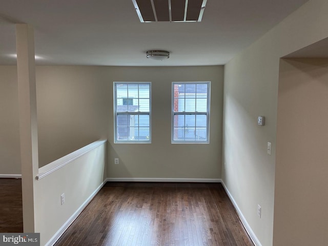 spare room with visible vents, baseboards, and dark wood finished floors