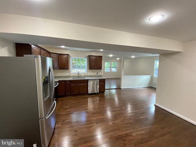 kitchen featuring dark wood-style flooring, stainless steel appliances, light countertops, a sink, and dark brown cabinetry