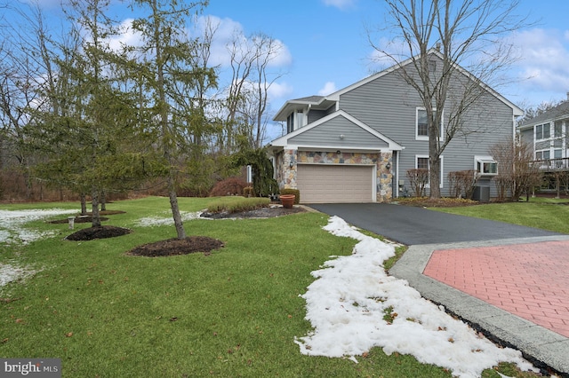 view of front of home featuring central AC unit, a garage, and a front lawn