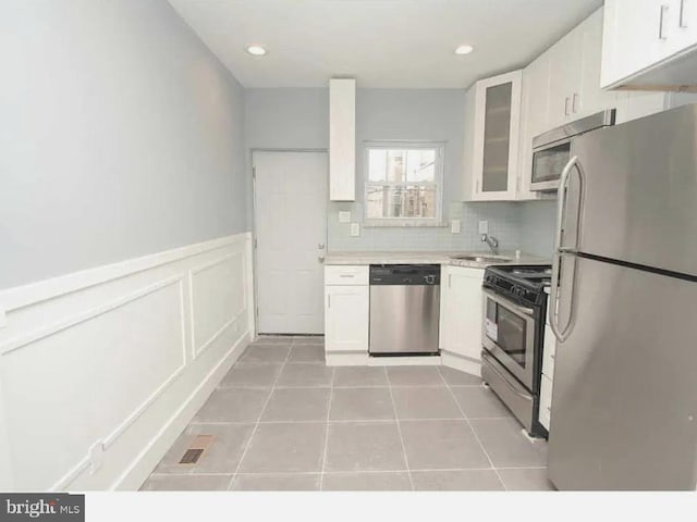 kitchen with light tile patterned floors, stainless steel appliances, light countertops, and white cabinetry