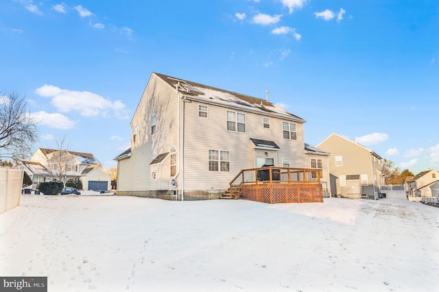 snow covered back of property with a deck