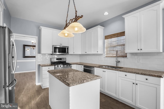 kitchen featuring a kitchen island, decorative light fixtures, sink, white cabinets, and stainless steel appliances