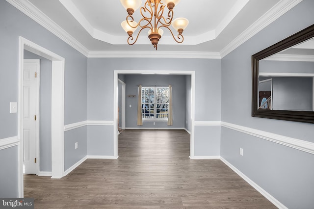 unfurnished dining area featuring dark hardwood / wood-style flooring, a chandelier, and a raised ceiling