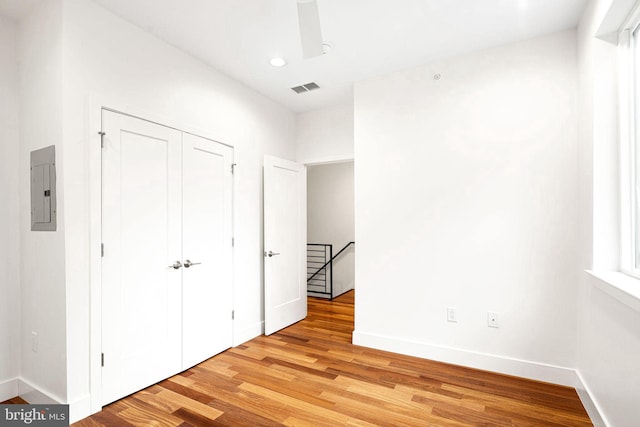 unfurnished bedroom featuring light wood-style flooring, electric panel, visible vents, and baseboards