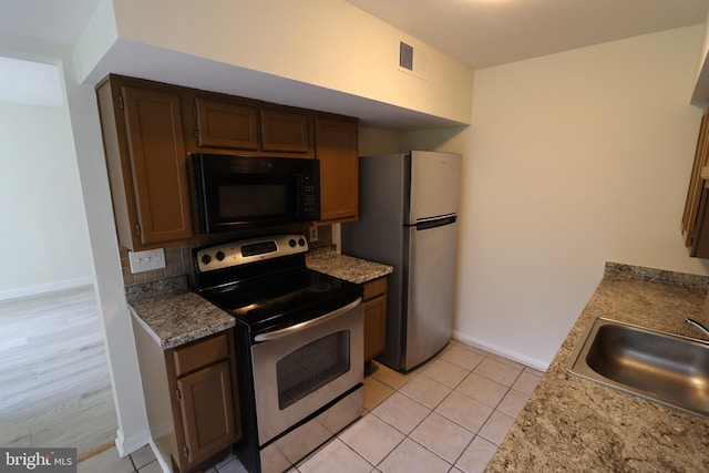 kitchen with tasteful backsplash, appliances with stainless steel finishes, sink, and light tile patterned floors