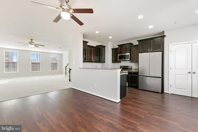 kitchen with dark wood-style floors, stainless steel appliances, light countertops, and open floor plan