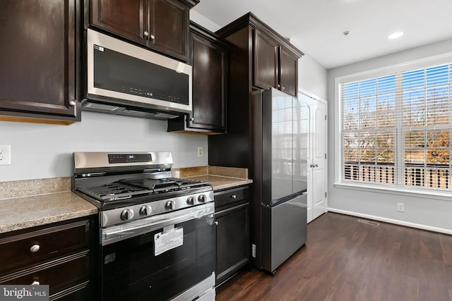 kitchen with stainless steel appliances, dark brown cabinets, dark wood-style flooring, and light countertops