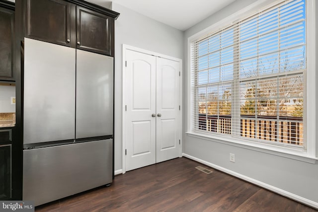 kitchen with freestanding refrigerator, dark wood-style flooring, visible vents, and dark brown cabinetry