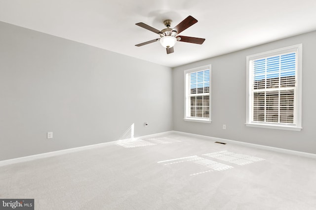 unfurnished room with visible vents, baseboards, a ceiling fan, and light colored carpet