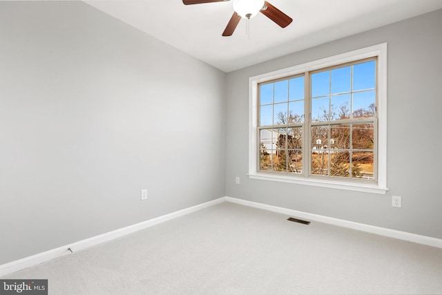 carpeted spare room featuring ceiling fan, visible vents, and baseboards