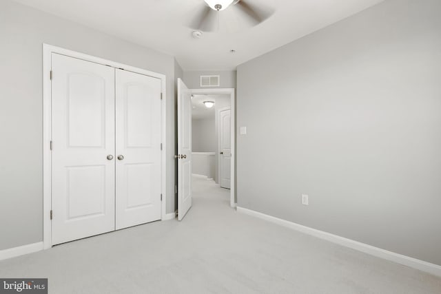 unfurnished bedroom with baseboards, visible vents, a closet, and light colored carpet