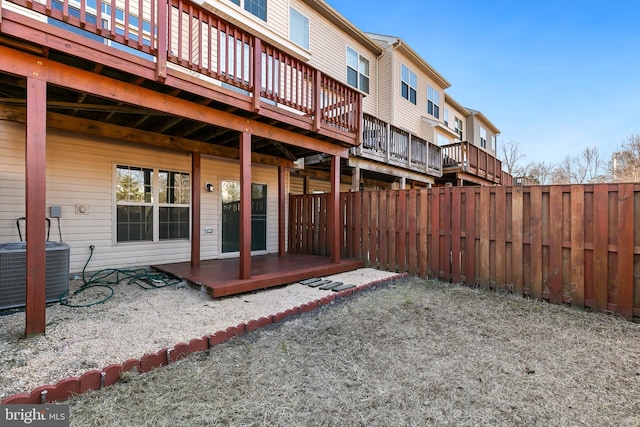 rear view of house with fence, a deck, and central AC unit