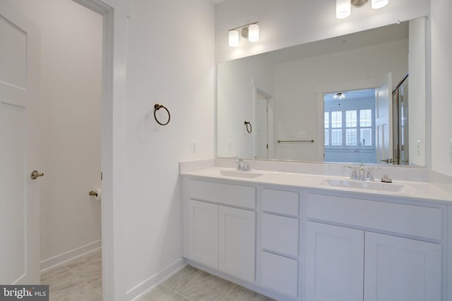 bathroom with double vanity, baseboards, and a sink