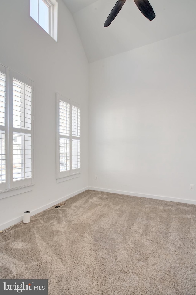 carpeted spare room with high vaulted ceiling, a wealth of natural light, visible vents, and baseboards