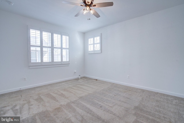 spare room with light colored carpet, ceiling fan, and baseboards