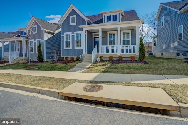 bungalow featuring covered porch, central AC, a shingled roof, board and batten siding, and a front yard