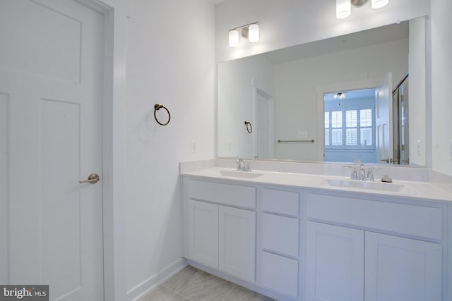 bathroom with double vanity, a sink, and baseboards