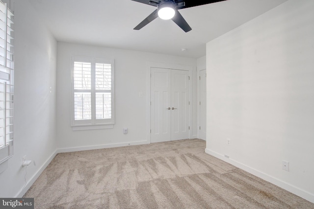 interior space with light carpet, ceiling fan, and baseboards