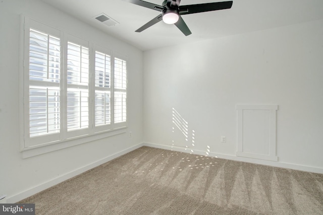 carpeted spare room featuring a ceiling fan, visible vents, and baseboards