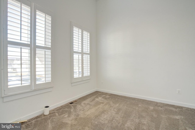 spare room with carpet floors, visible vents, and baseboards