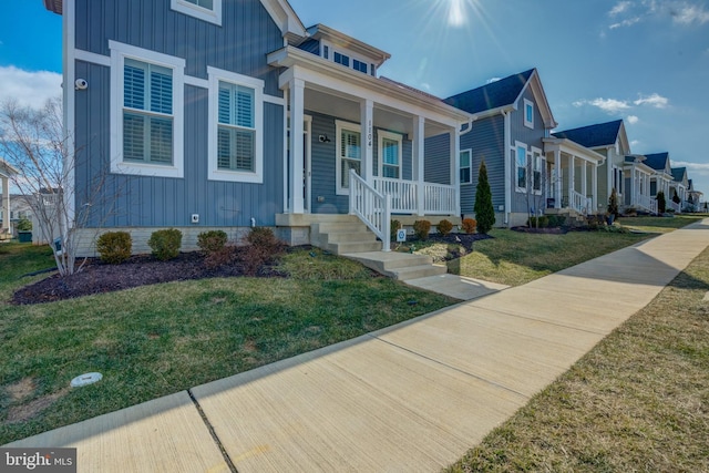 view of front facade featuring a residential view, a porch, board and batten siding, and a front yard