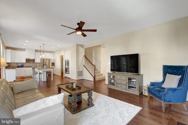 living room featuring dark wood-type flooring and ceiling fan