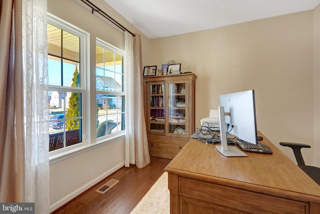 office space with a healthy amount of sunlight and dark hardwood / wood-style flooring