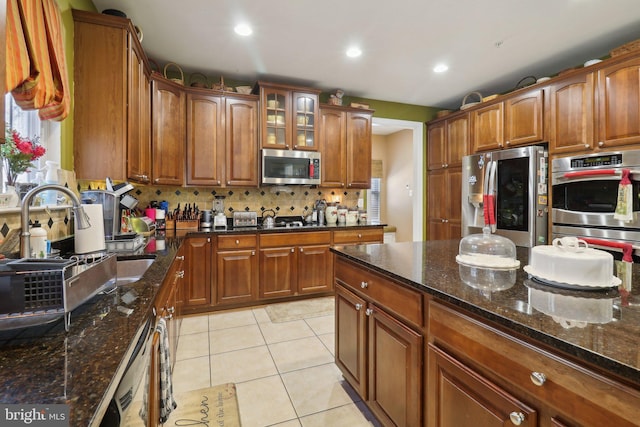 kitchen with dark stone counters, light tile patterned flooring, tasteful backsplash, and stainless steel appliances