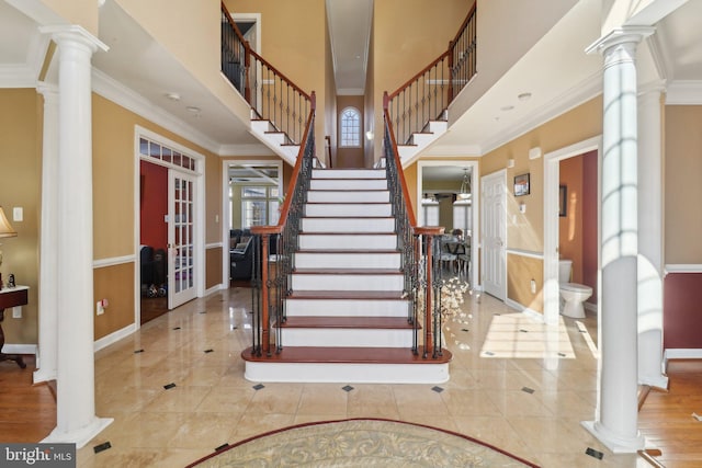 tiled entryway featuring crown molding, french doors, ornate columns, and a towering ceiling