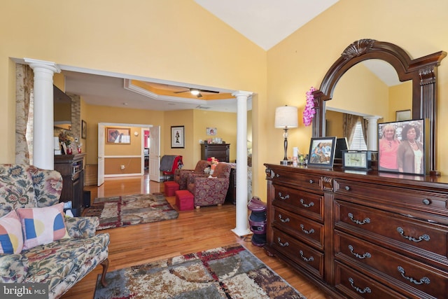 living area featuring hardwood / wood-style flooring, ornate columns, and lofted ceiling