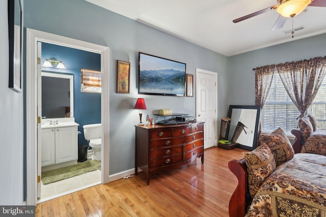 bedroom featuring ensuite bathroom, light hardwood / wood-style floors, sink, and ceiling fan