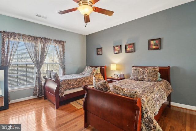 bedroom featuring multiple windows, hardwood / wood-style floors, and ceiling fan