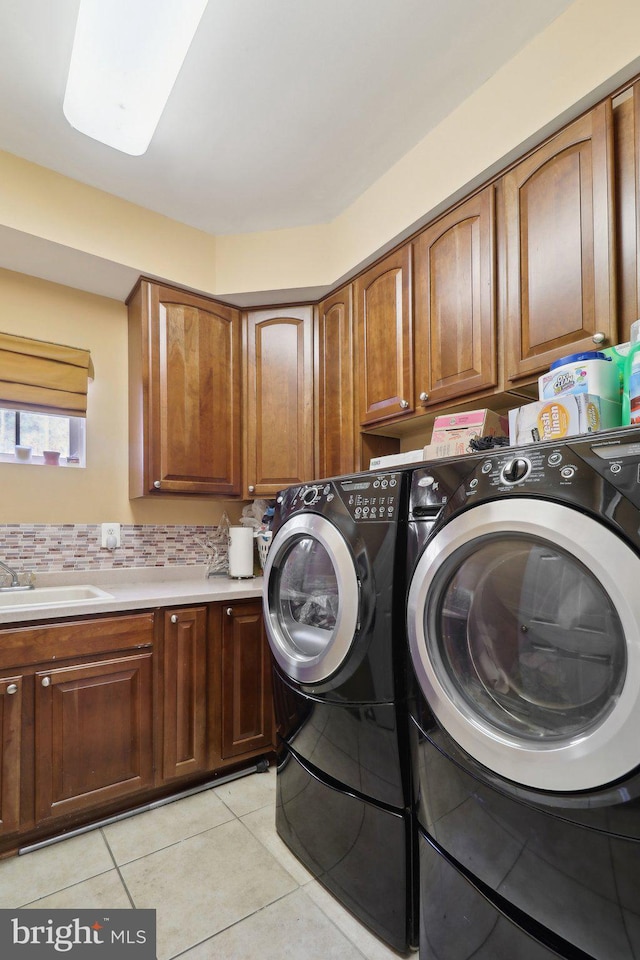 washroom with sink, cabinets, washer and dryer, and light tile patterned floors