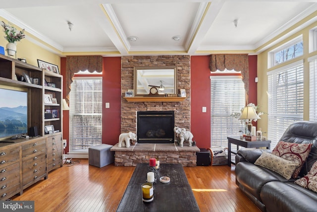 living room featuring hardwood / wood-style flooring, a stone fireplace, ornamental molding, and beam ceiling