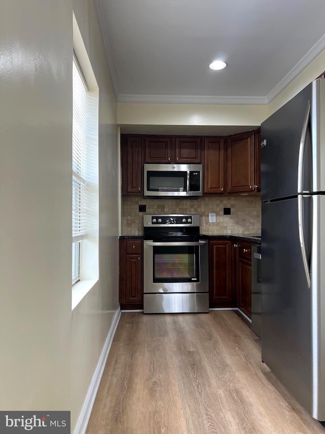 kitchen with backsplash, crown molding, stainless steel appliances, and light hardwood / wood-style floors