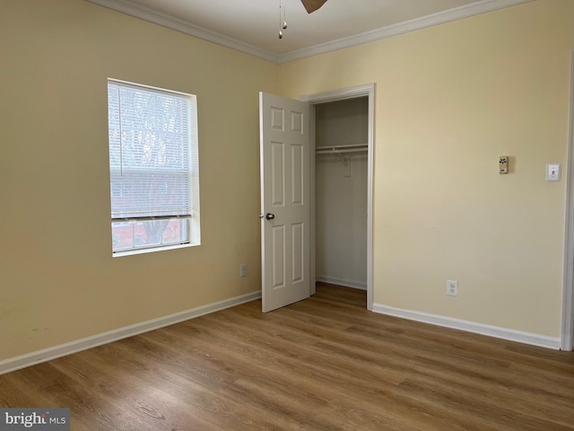 unfurnished bedroom with hardwood / wood-style floors, crown molding, and a closet