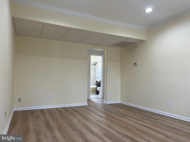 spare room with ornamental molding, hardwood / wood-style floors, and a drop ceiling