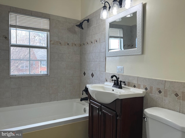 full bathroom featuring vanity, toilet, tiled shower / bath combo, and tile walls