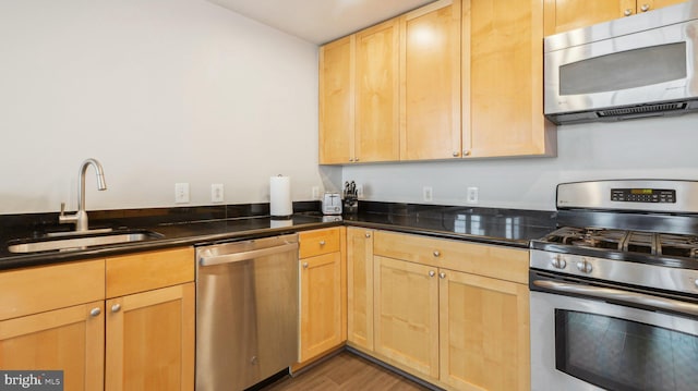 kitchen with stainless steel appliances, sink, dark stone countertops, and dark hardwood / wood-style floors