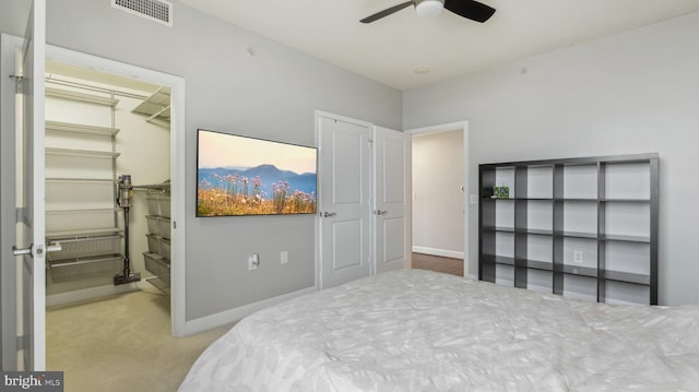 carpeted bedroom with ceiling fan, a walk in closet, and a closet