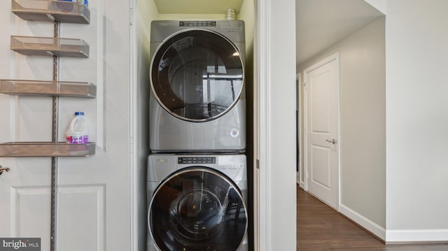 laundry area featuring dark hardwood / wood-style flooring and stacked washer and dryer