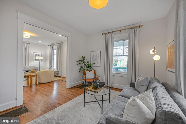 living room with baseboards, visible vents, and wood finished floors