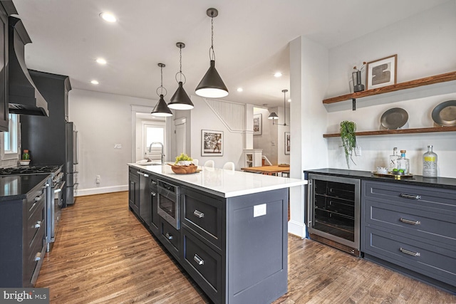 kitchen with appliances with stainless steel finishes, wine cooler, dark wood finished floors, and a sink