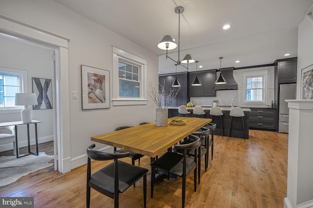 dining space featuring light wood finished floors, baseboards, and recessed lighting